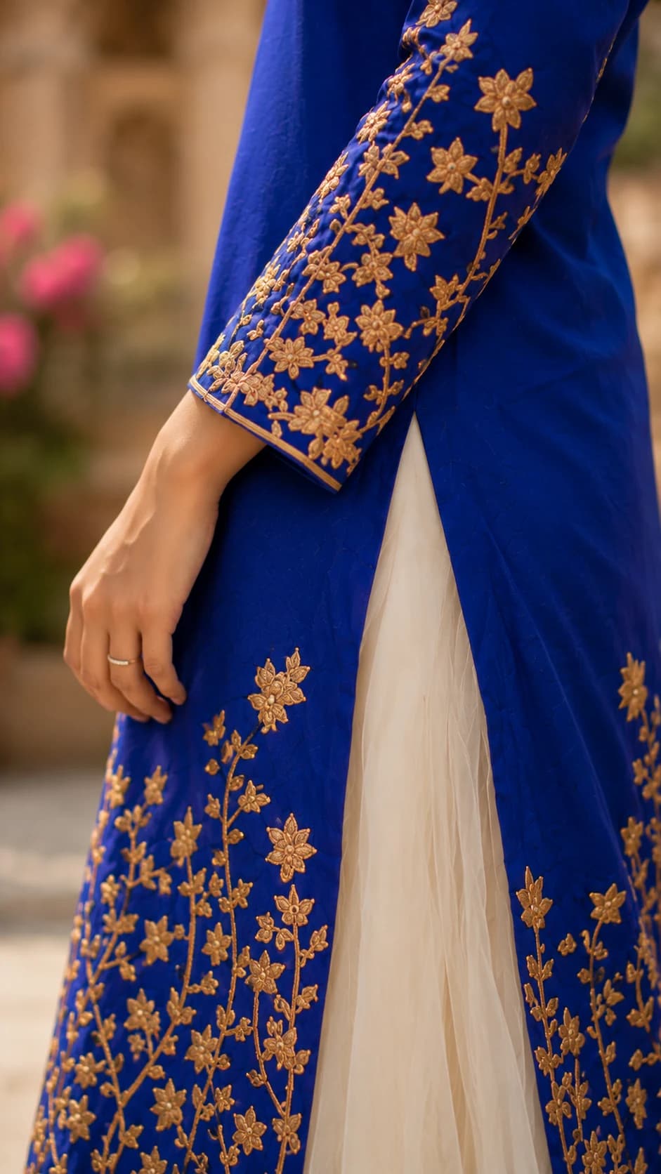 Close-up fashion photography highlighting gold floral embroidery and fabric detail