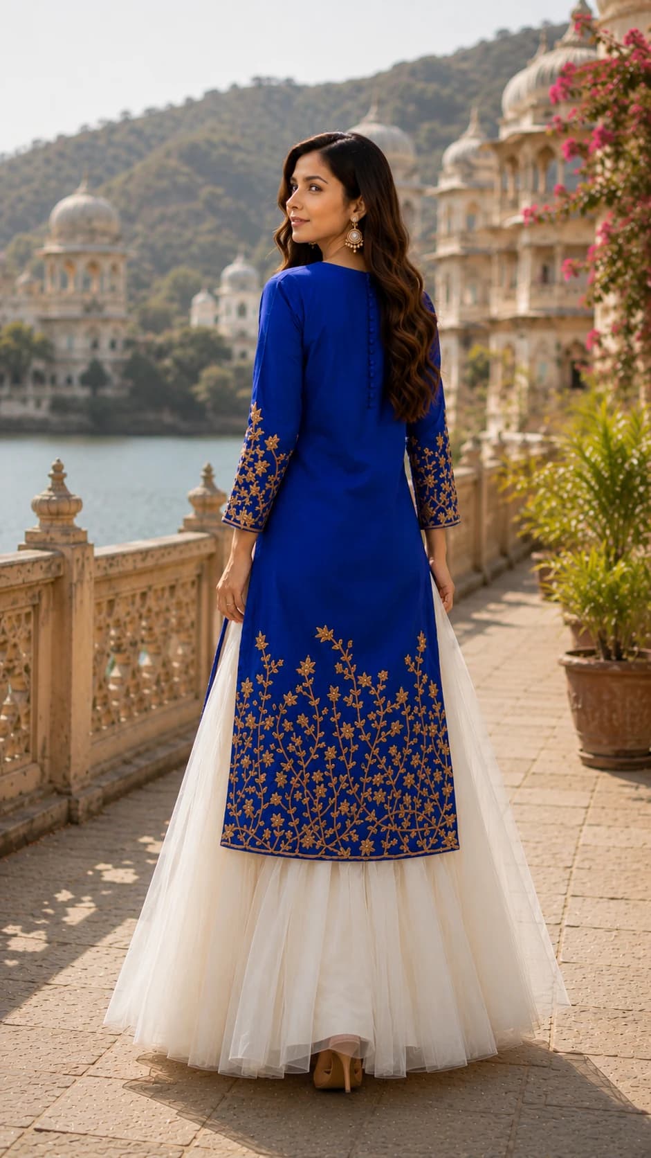 Back-view fashion campaign portrait showcasing embroidered blue outerwear and flowing white skirt